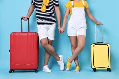 Woman and man with suitcases on light blue background, closeup