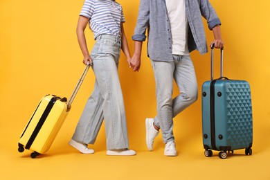 Photo of Couple with suitcases on orange background, closeup