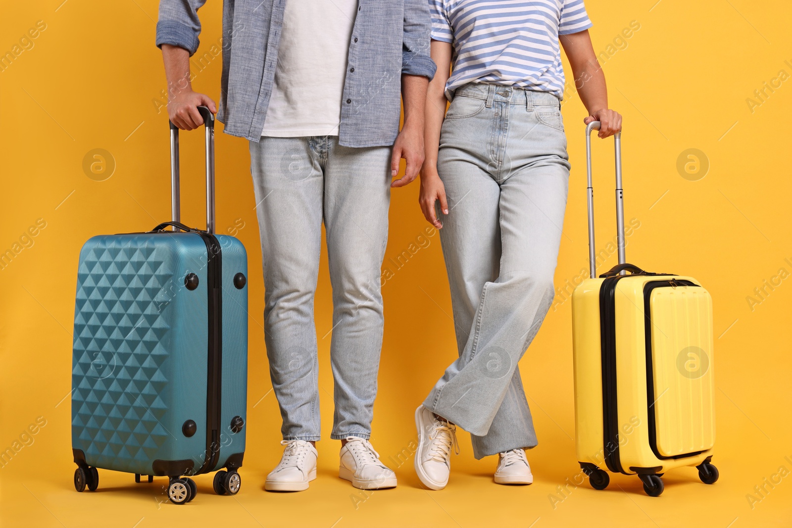 Photo of Couple with suitcases on orange background, closeup