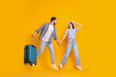 Photo of Happy man with suitcase and woman running on orange background