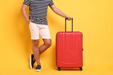 Man with suitcase on orange background, closeup