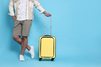 Photo of Man with suitcase on light blue background, closeup. Space for text