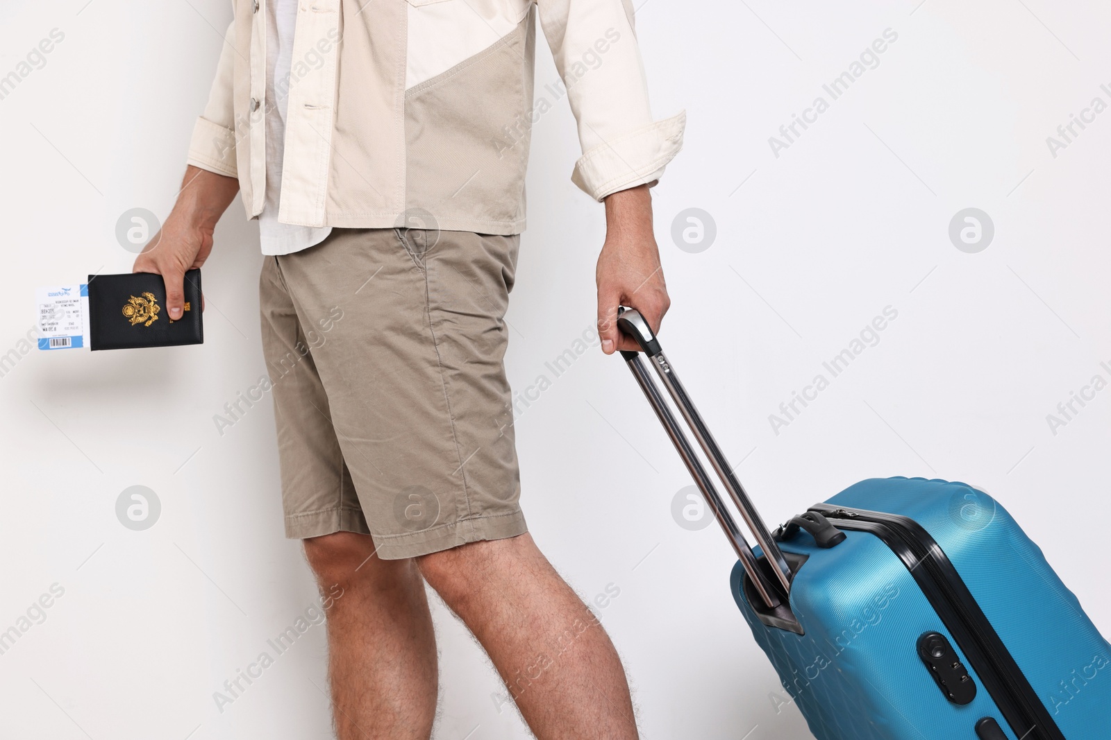 Photo of Man with suitcase, passport and ticket on light background, closeup