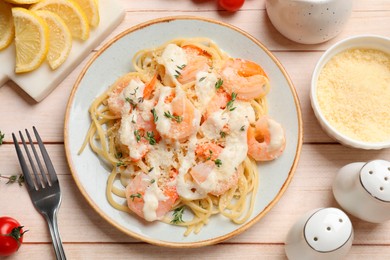 Photo of Tasty pasta with shrimps, creamy sauce and cheese on light wooden table, flat lay