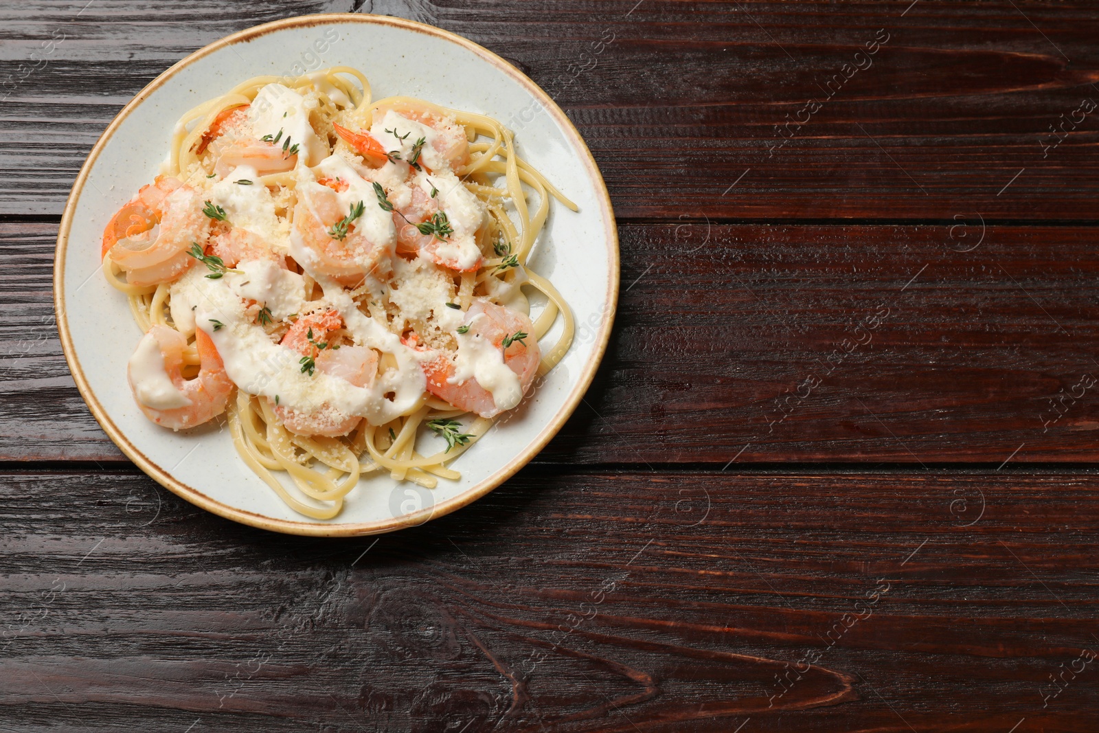 Photo of Tasty pasta with shrimps, creamy sauce and cheese on wooden table, top view. Space for text