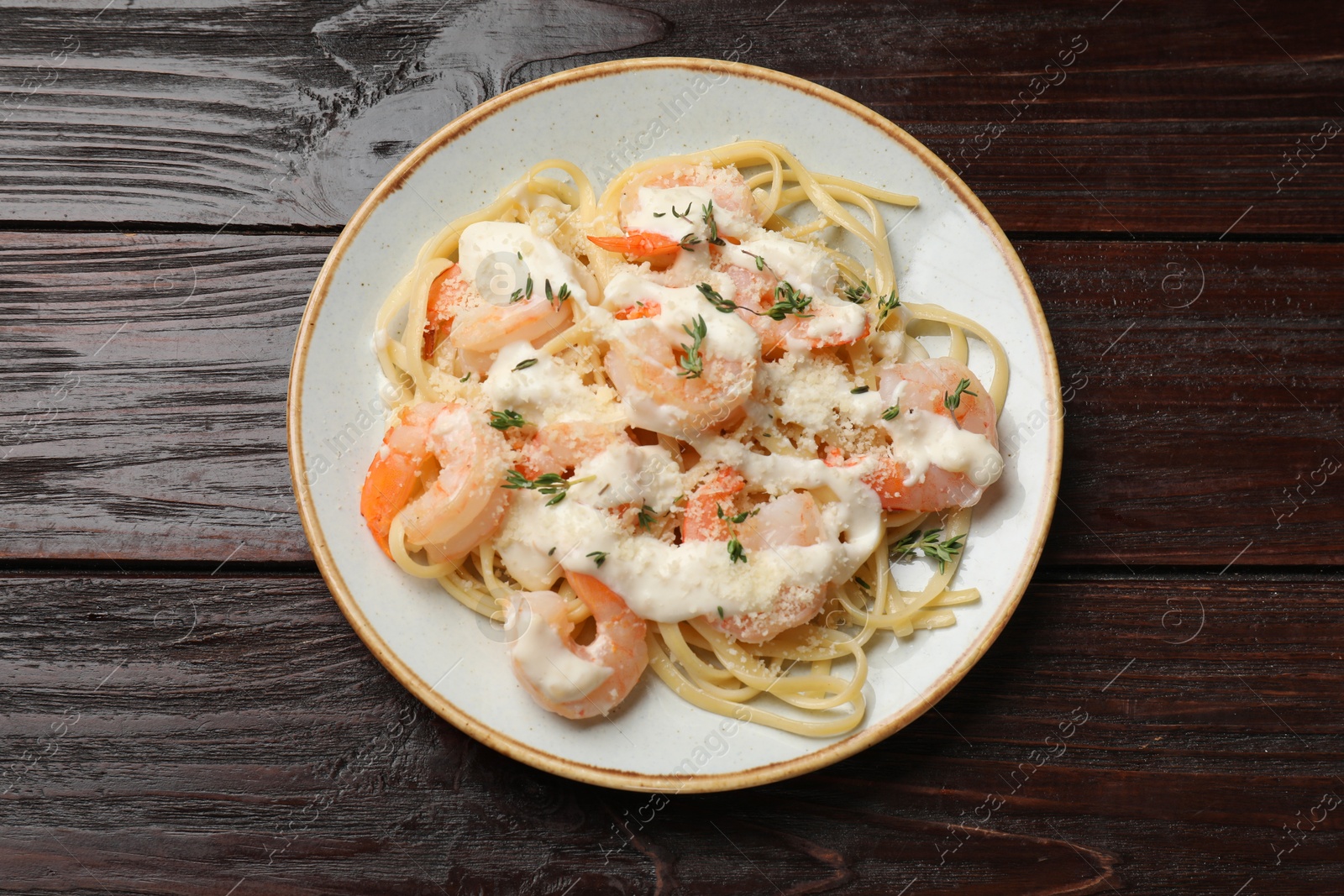 Photo of Tasty pasta with shrimps, creamy sauce and cheese on wooden table, top view