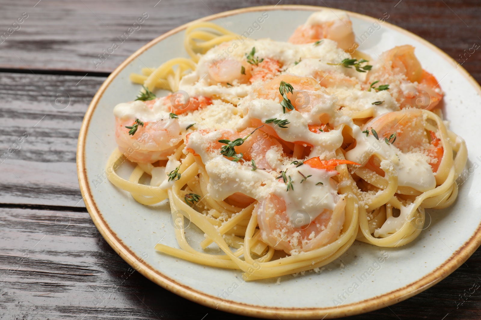 Photo of Tasty pasta with shrimps, creamy sauce and cheese on wooden table, closeup