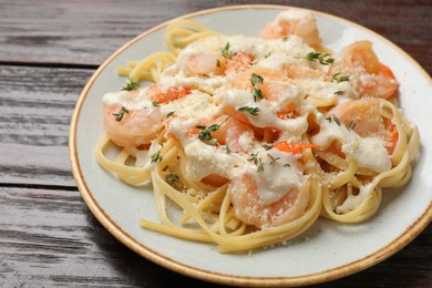 Photo of Tasty pasta with shrimps, creamy sauce and cheese on wooden table, closeup