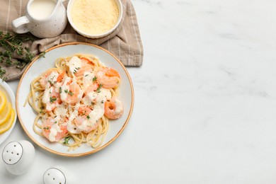 Photo of Tasty pasta with shrimps, creamy sauce and cheese served on white marble table, flat lay. Space for text