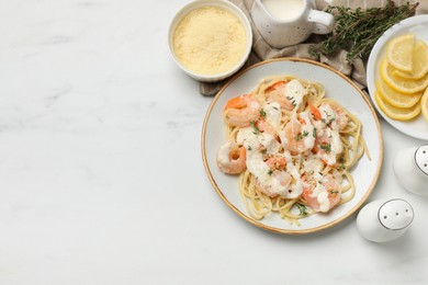 Photo of Tasty pasta with shrimps, creamy sauce and cheese served on white marble table, flat lay. Space for text