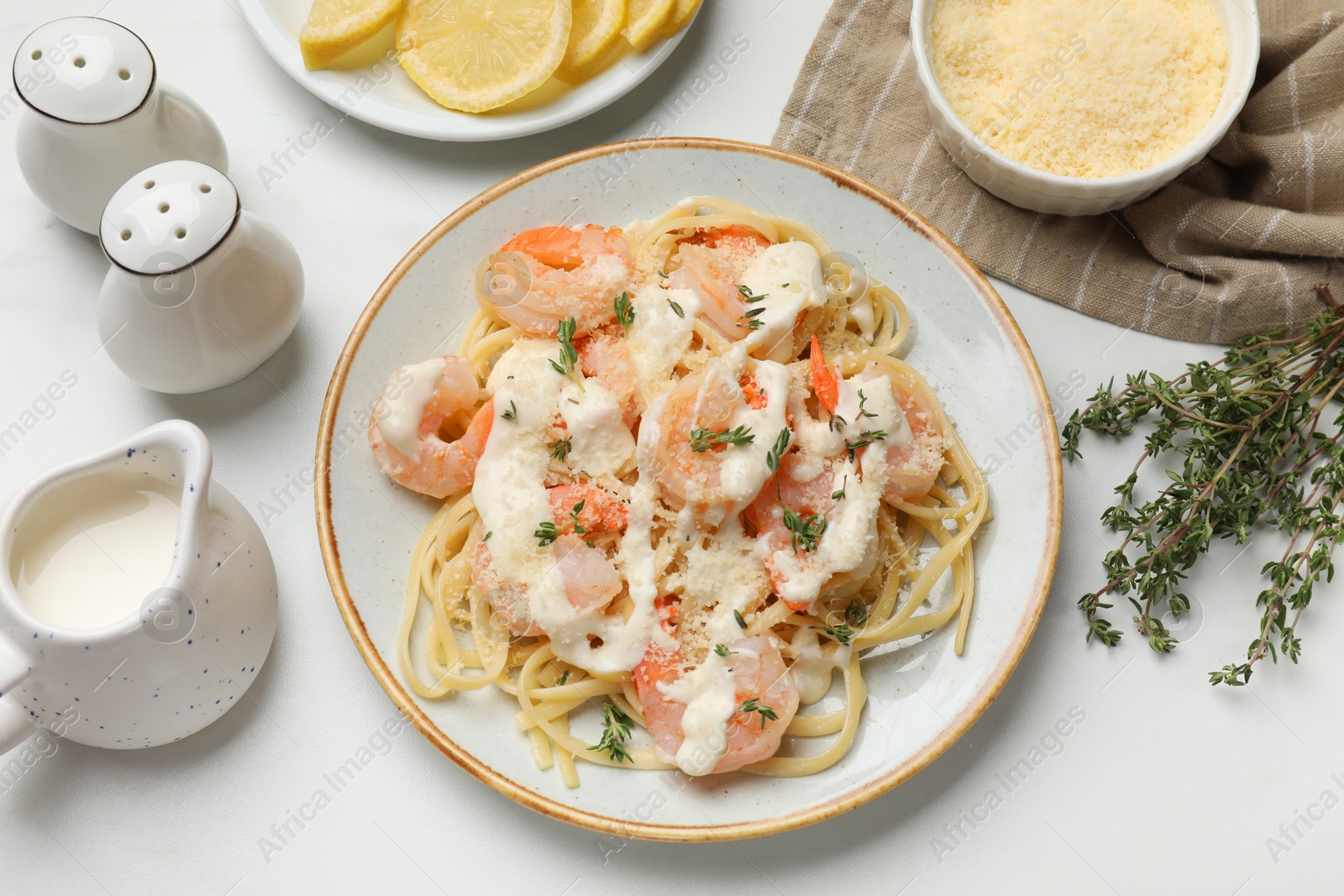 Photo of Tasty pasta with shrimps, creamy sauce and cheese served on white table, flat lay