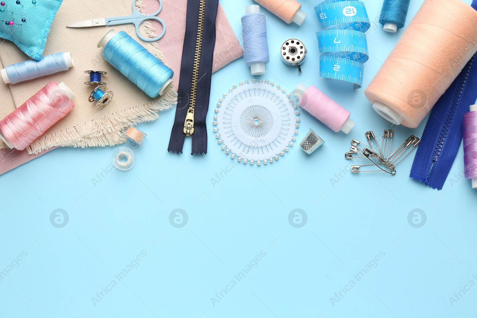 Photo of Flat lay composition with different sewing supplies on light blue background. Space for text