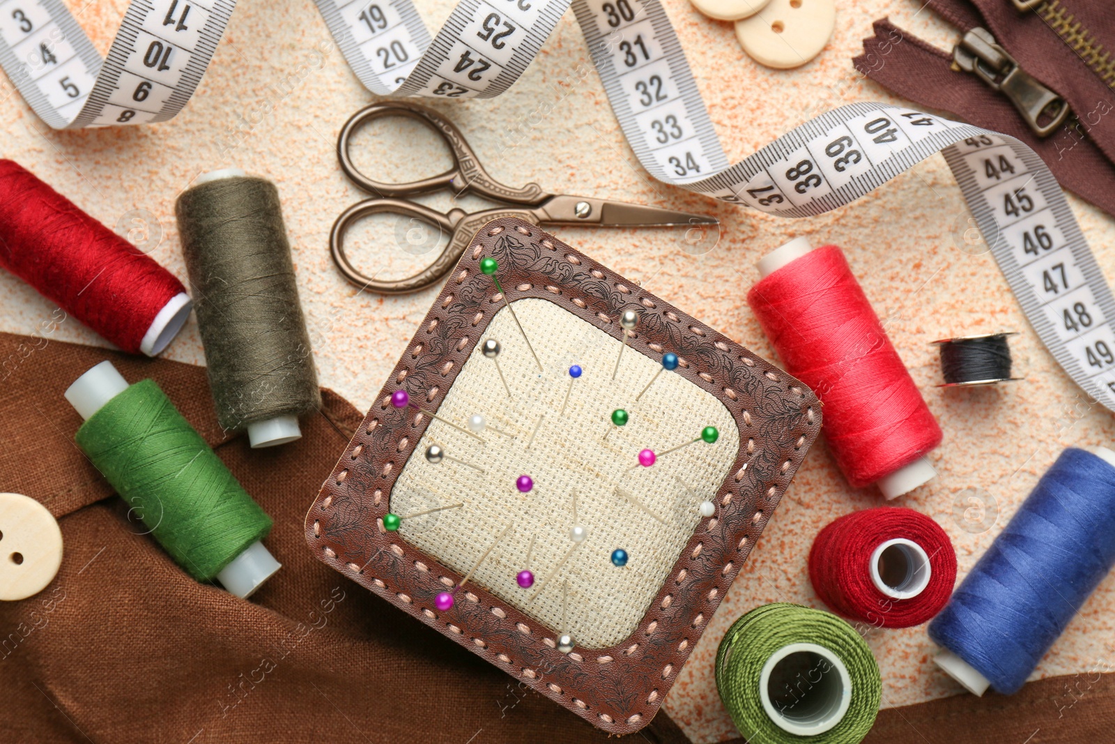 Photo of Flat lay composition with different sewing supplies on beige textured table