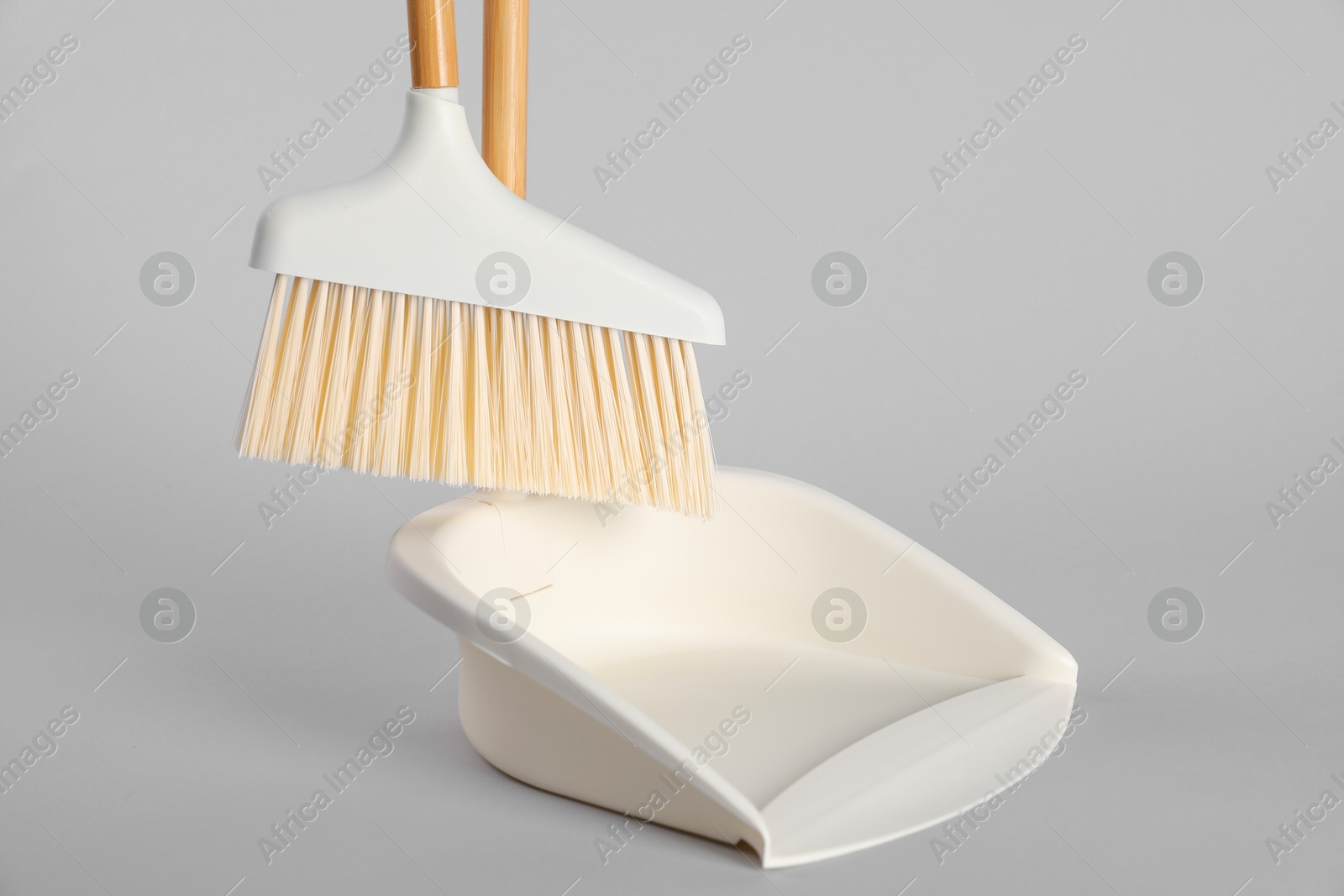 Photo of Cleaning broom and dustpan on grey background