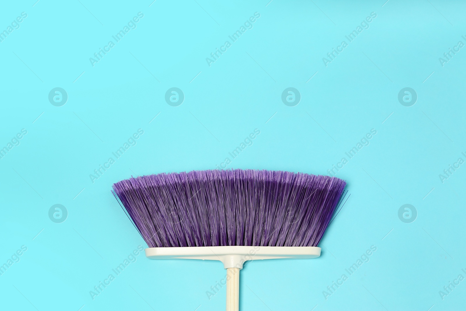 Photo of One cleaning broom on light blue background, top view