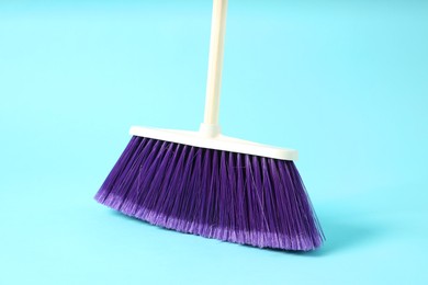 Photo of One cleaning broom on light blue background