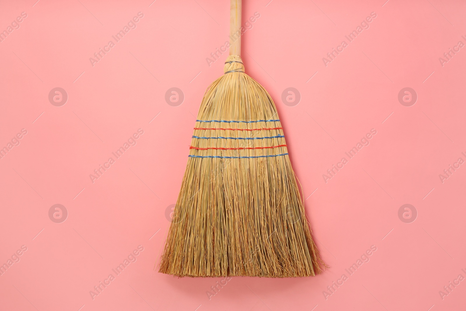 Photo of One corn straw broom on pink background, top view