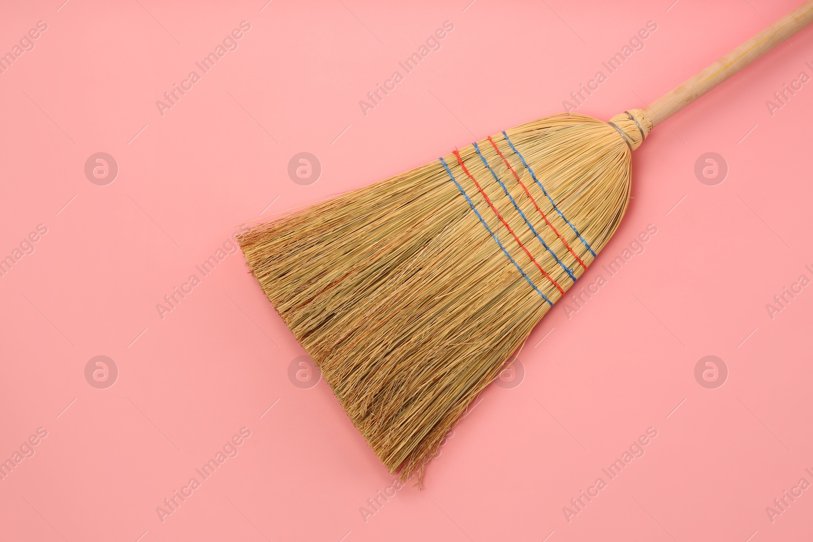 Photo of One corn straw broom on pink background, top view