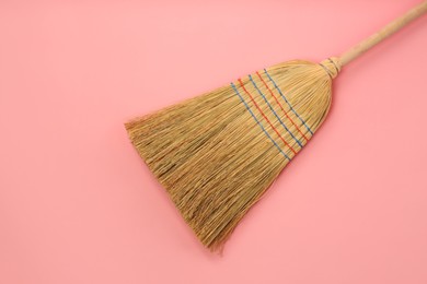 Photo of One corn straw broom on pink background, top view