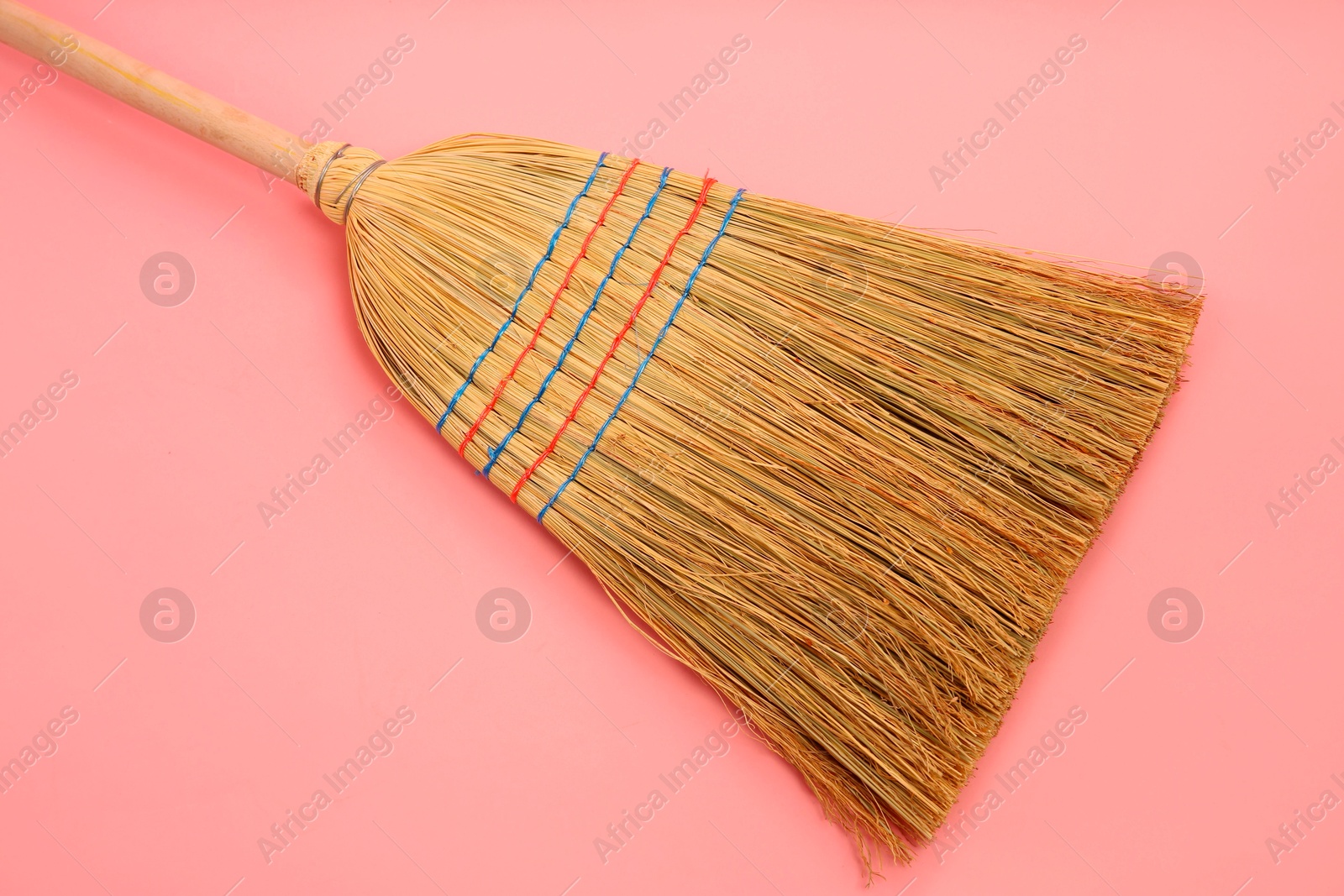 Photo of One corn straw broom on pink background, top view