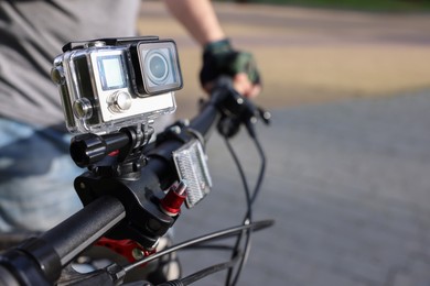 Man riding bicycle with modern action camera outdoors, closeup. Space for text