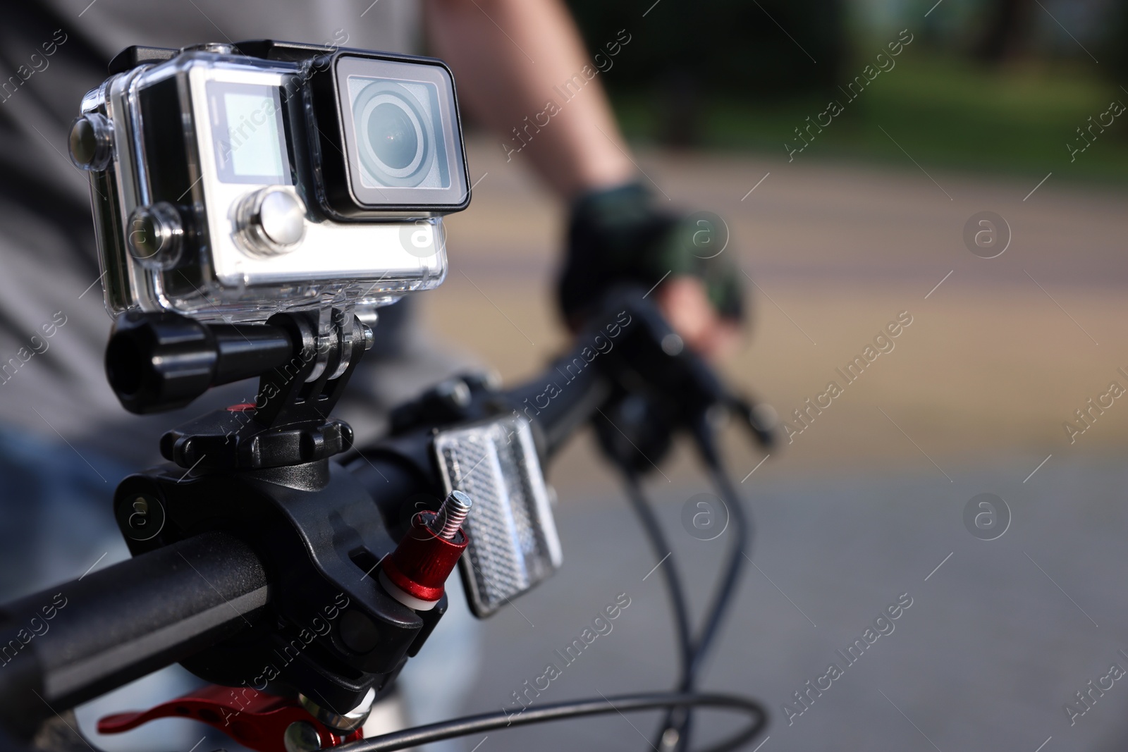 Photo of Man riding bicycle with modern action camera outdoors, closeup. Space for text