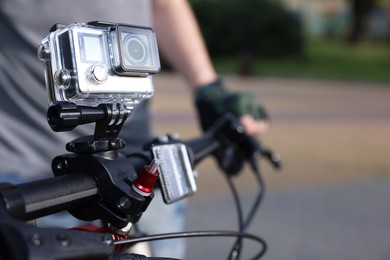 Photo of Man riding bicycle with modern action camera outdoors, closeup. Space for text