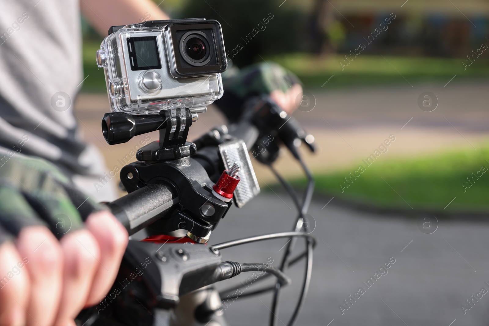 Photo of Man riding bicycle with modern action camera outdoors, closeup. Space for text