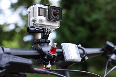 Photo of Modern action camera with mount on bicycle outdoors, closeup