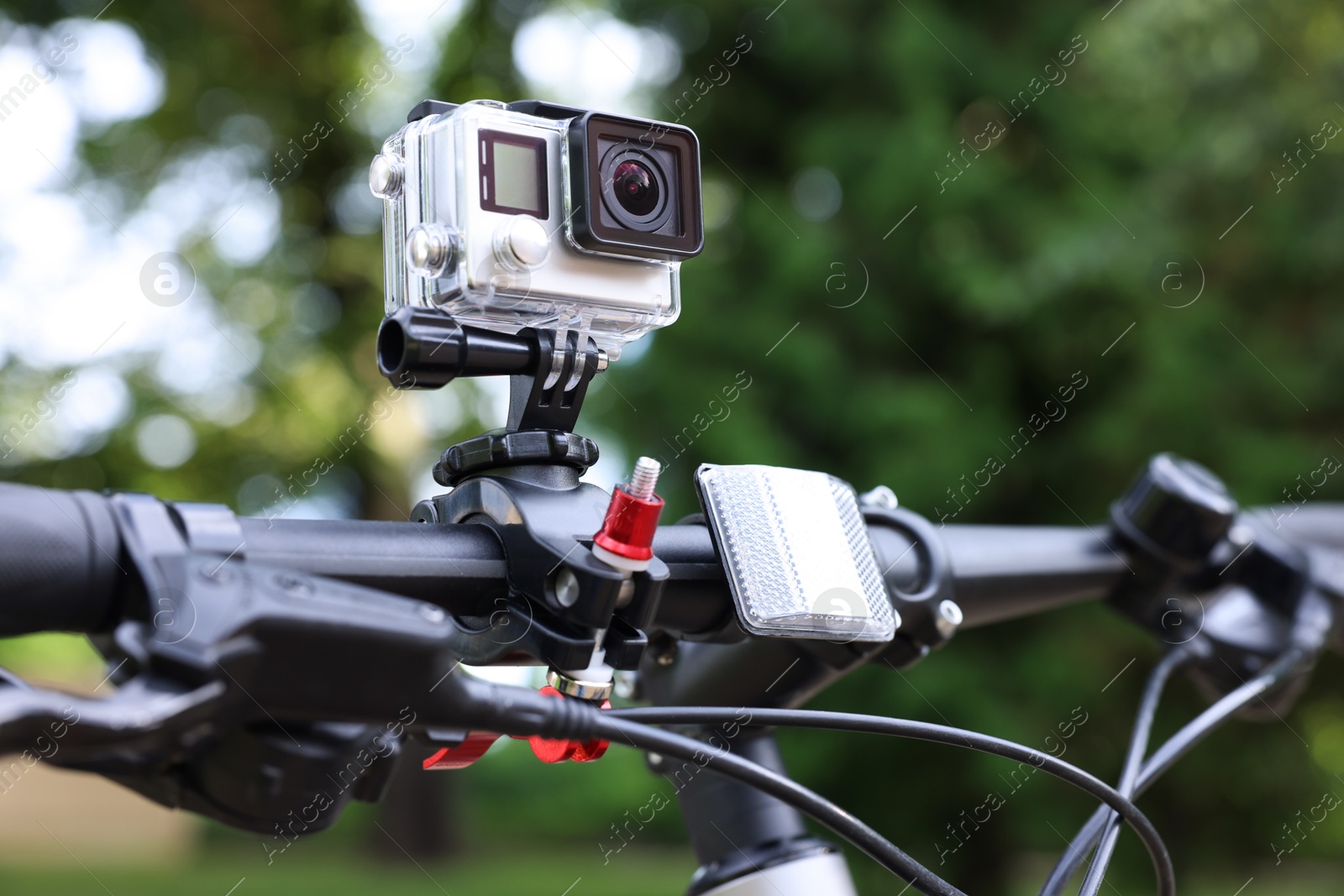 Photo of Modern action camera with mount on bicycle outdoors, closeup