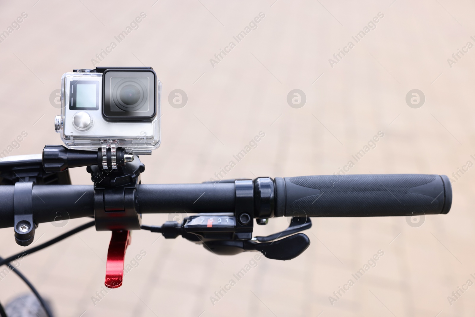 Photo of Modern action camera with mount on bicycle outdoors, closeup