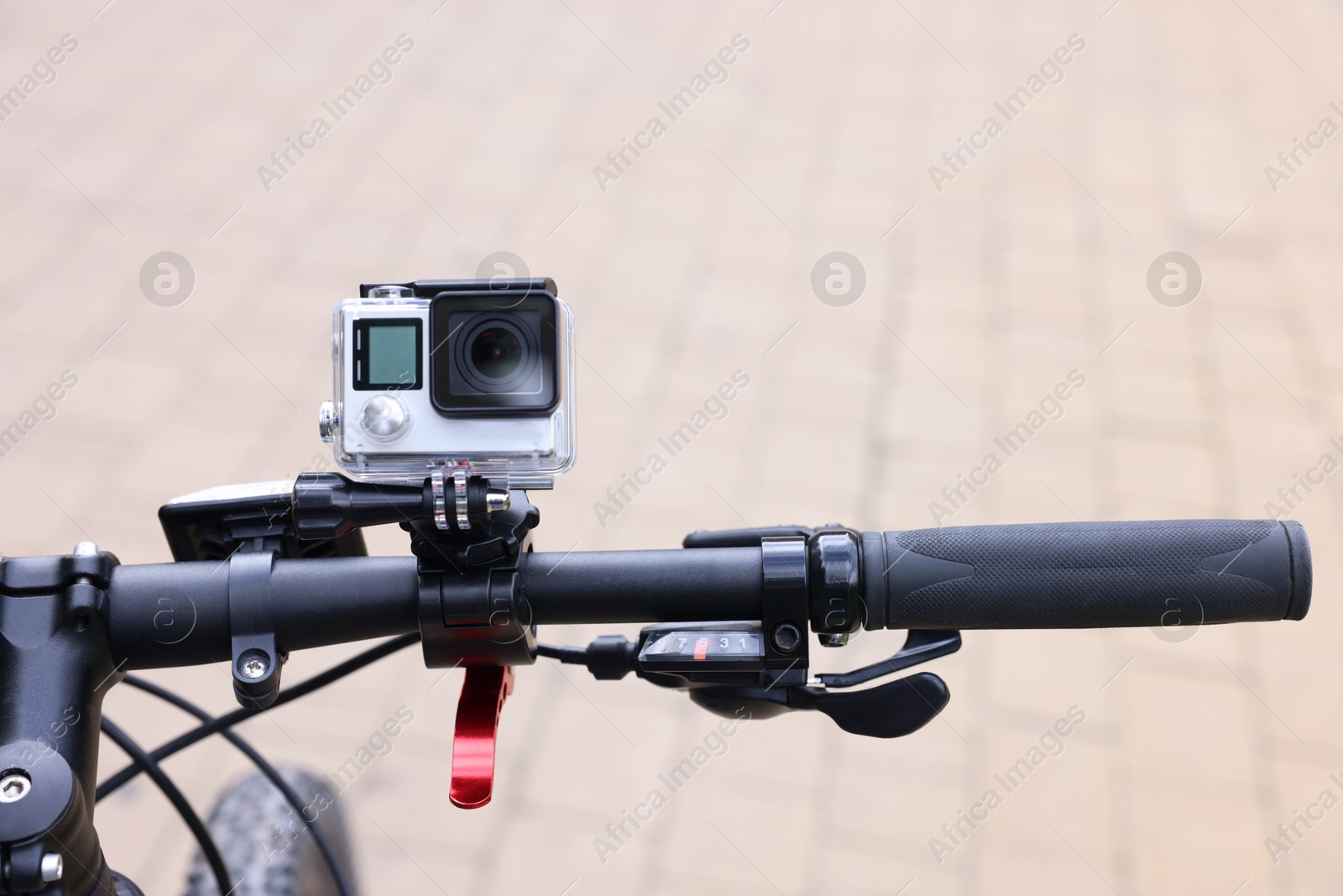 Photo of Modern action camera with mount on bicycle outdoors, closeup