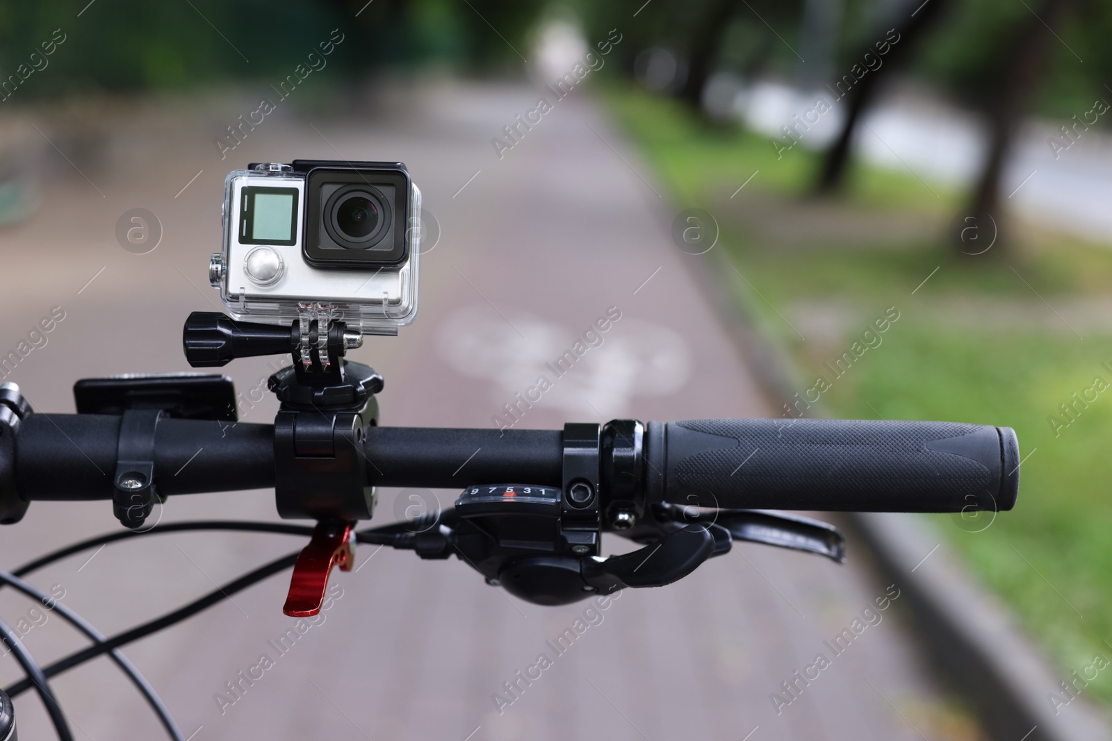 Photo of Modern action camera with mount on bicycle outdoors, closeup