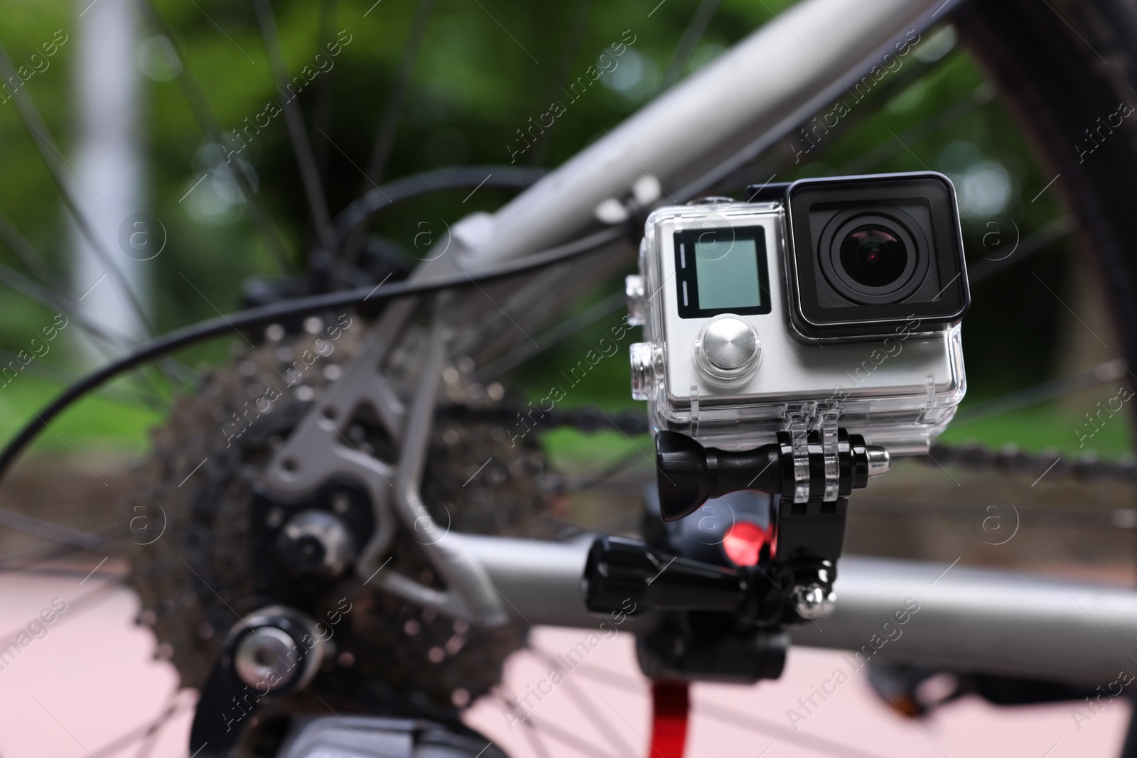 Photo of Modern action camera with mount on bicycle outdoors. Space for text