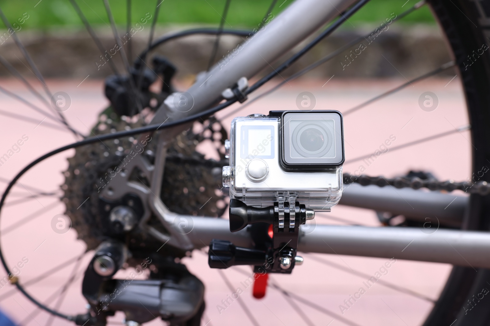 Photo of Modern action camera with mount on bicycle outdoors, closeup