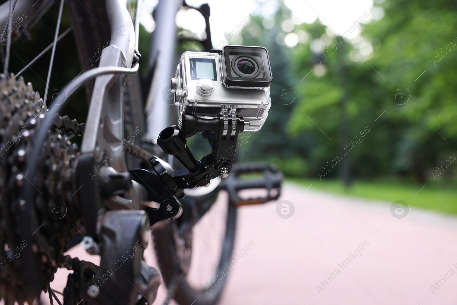 Photo of Modern action camera with mount on bicycle outdoors, closeup. Space for text