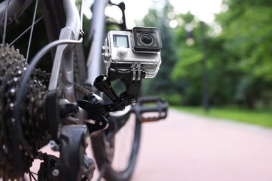 Modern action camera with mount on bicycle outdoors, closeup. Space for text