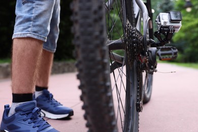 Man near bicycle with modern action camera outdoors, closeup