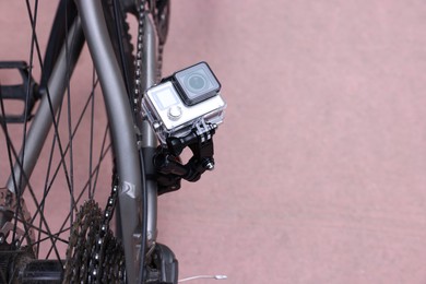 Modern action camera with mount on bicycle outdoors. Space for text