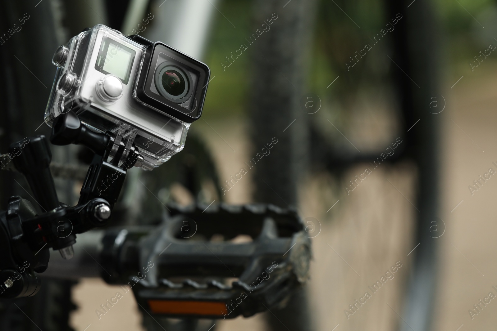 Photo of Modern action camera with mount on bicycle outdoors, closeup. Space for text