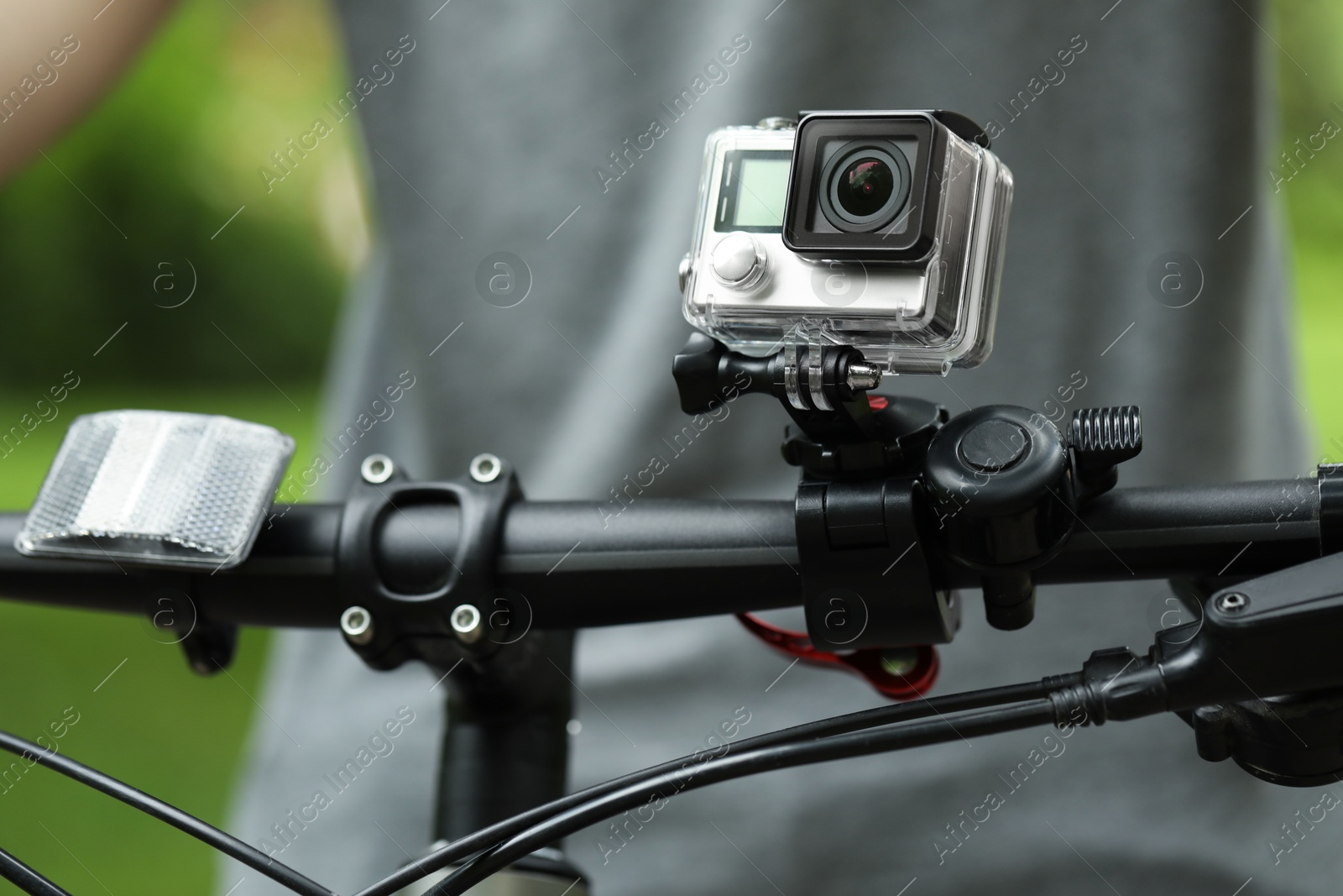 Photo of Man riding bicycle with modern action camera outdoors, closeup