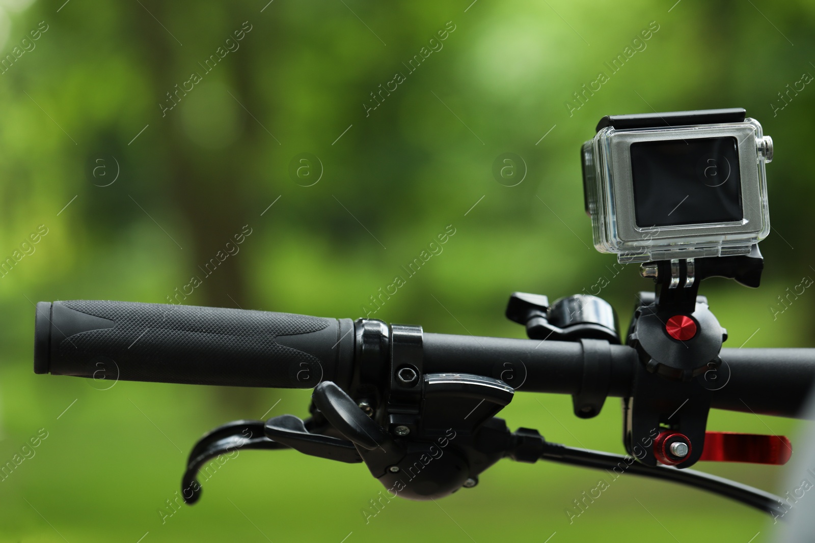 Photo of Modern action camera with mount on bicycle outdoors, closeup