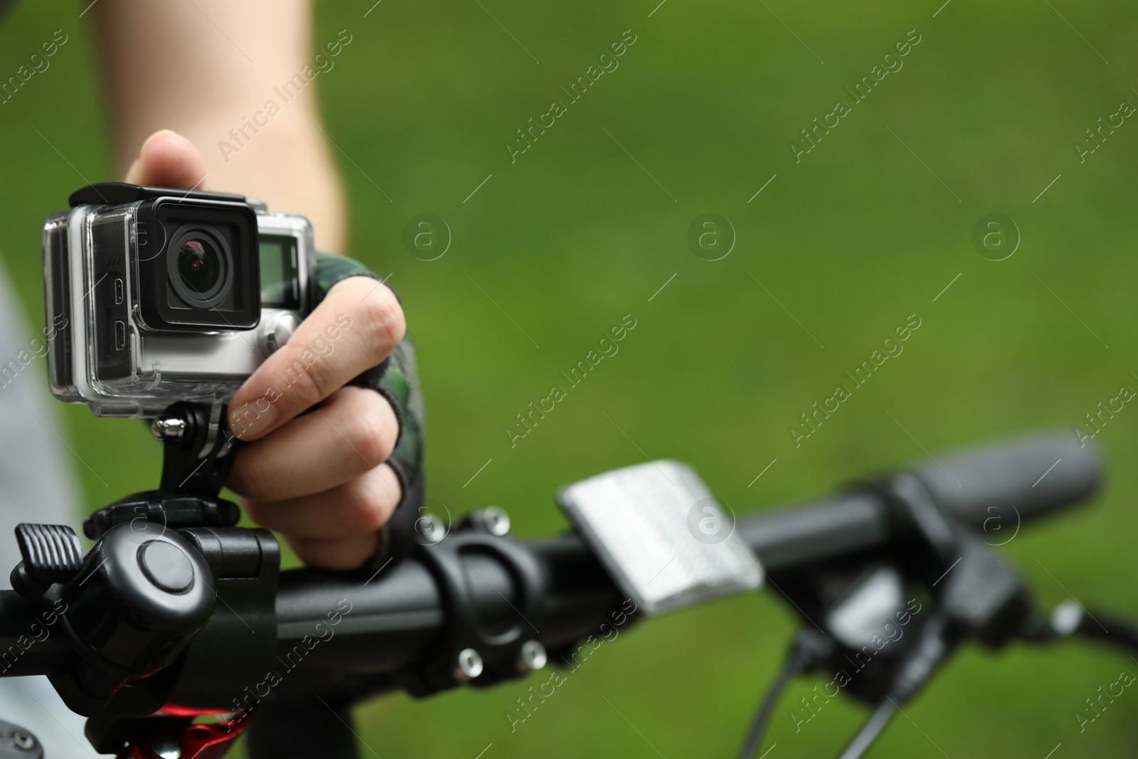 Photo of Man with modern action camera on bicycle outdoors, closeup. Space for text