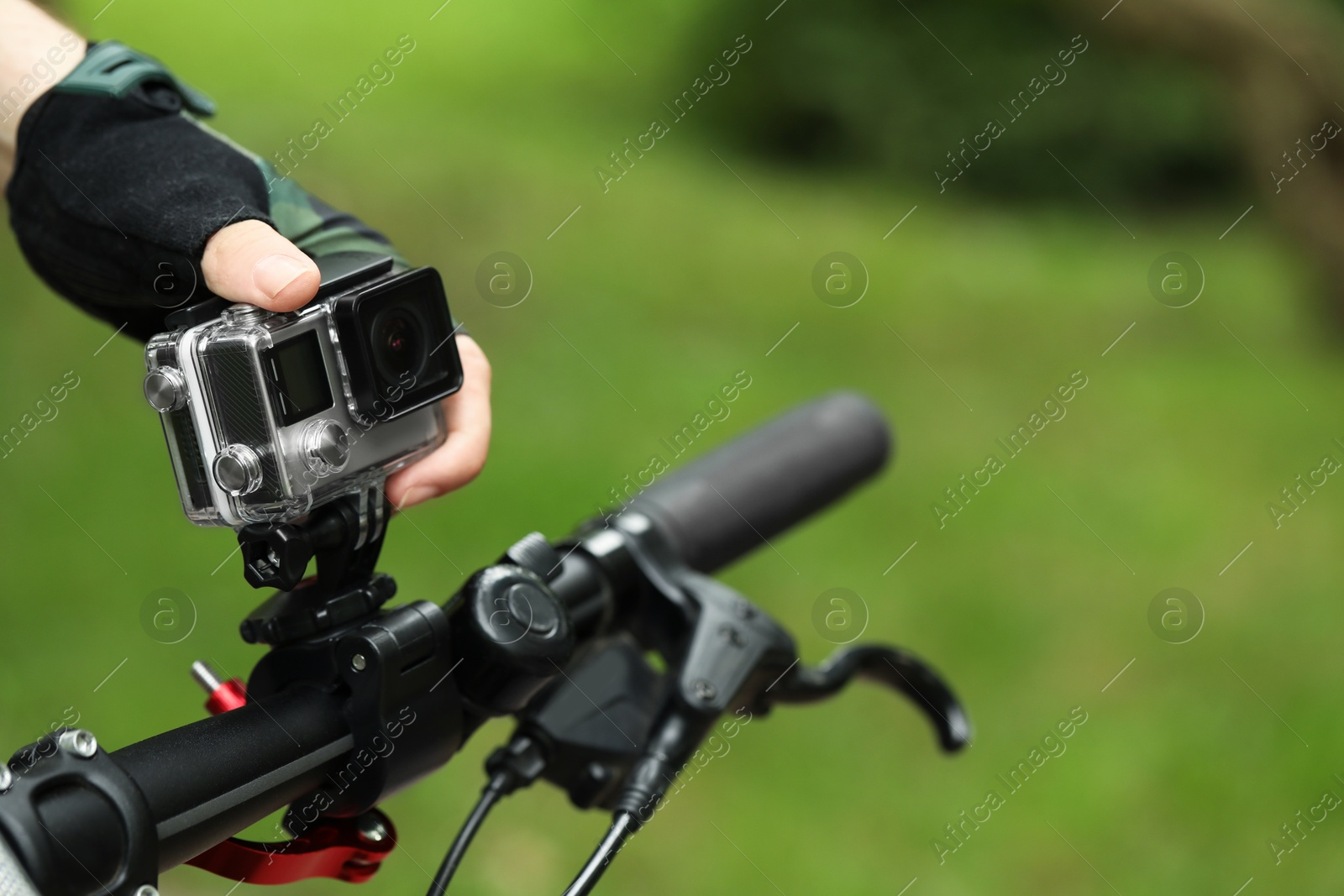 Photo of Man with modern action camera on bicycle outdoors, closeup. Space for text