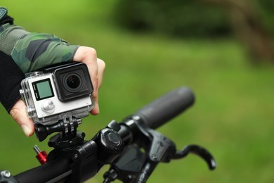 Man with modern action camera on bicycle outdoors, closeup. Space for text