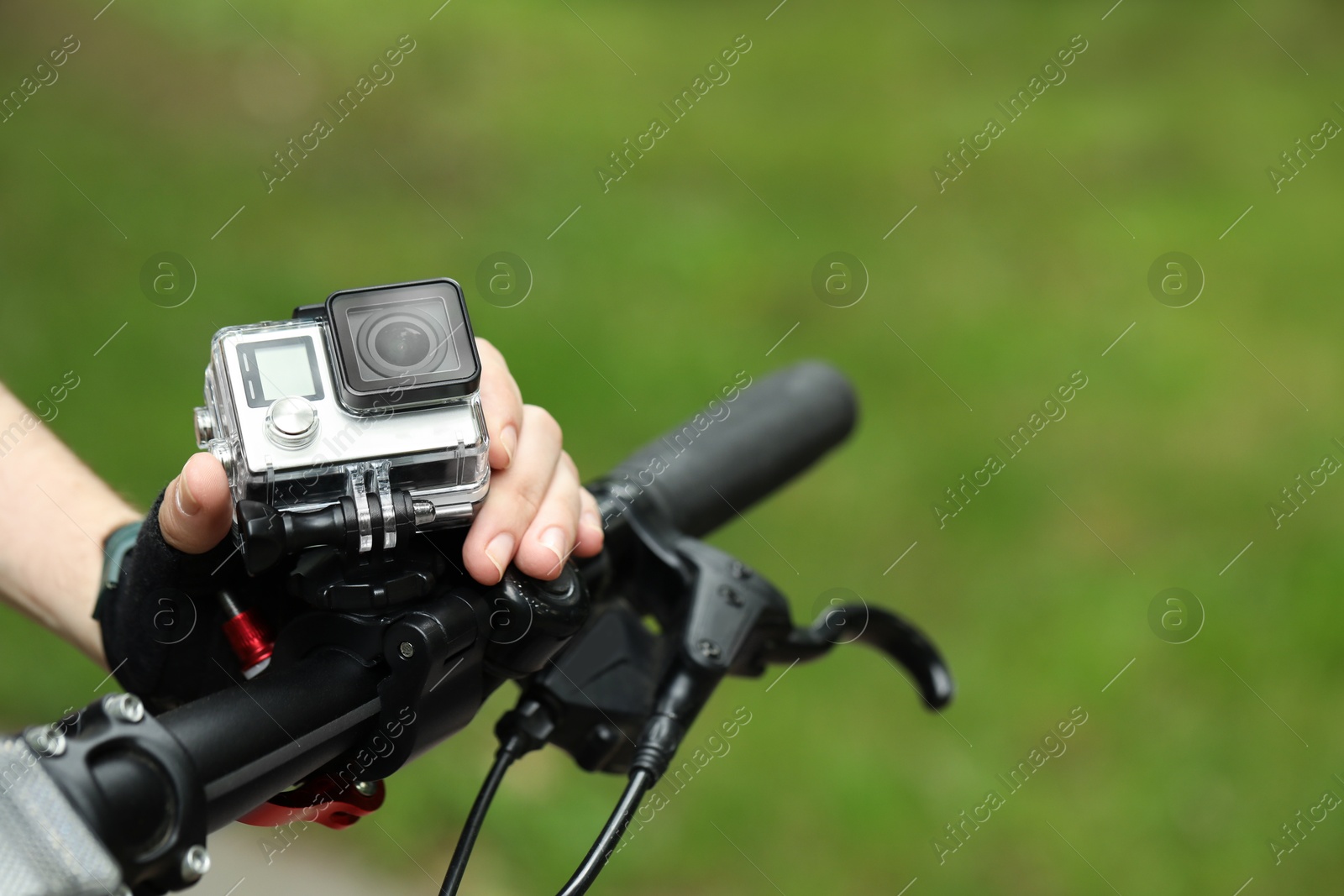 Photo of Man with modern action camera on bicycle outdoors, closeup. Space for text