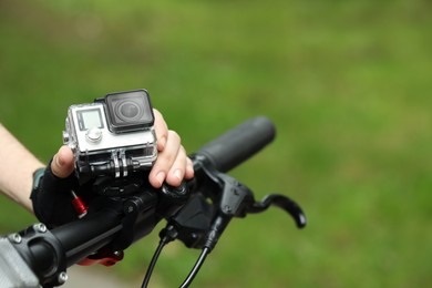 Man with modern action camera on bicycle outdoors, closeup. Space for text