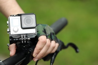 Man with modern action camera on bicycle outdoors, closeup. Space for text