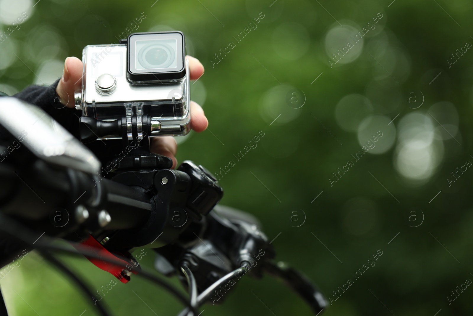 Photo of Man with modern action camera on bicycle outdoors, closeup. Space for text