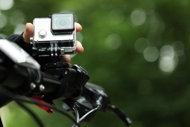 Man with modern action camera on bicycle outdoors, closeup. Space for text